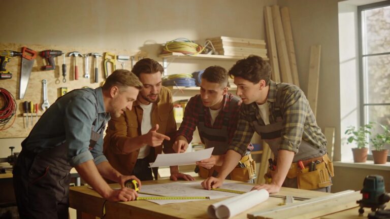 Trades professionals collaborating on project details in a workshop, highlighting teamwork and profitability focus